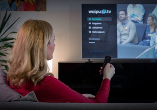 Eine Frau schaut auf ihrem Fernseher eine Sendung