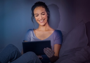 Eine Frau schaut in ihrem Bett auf ein Tablet